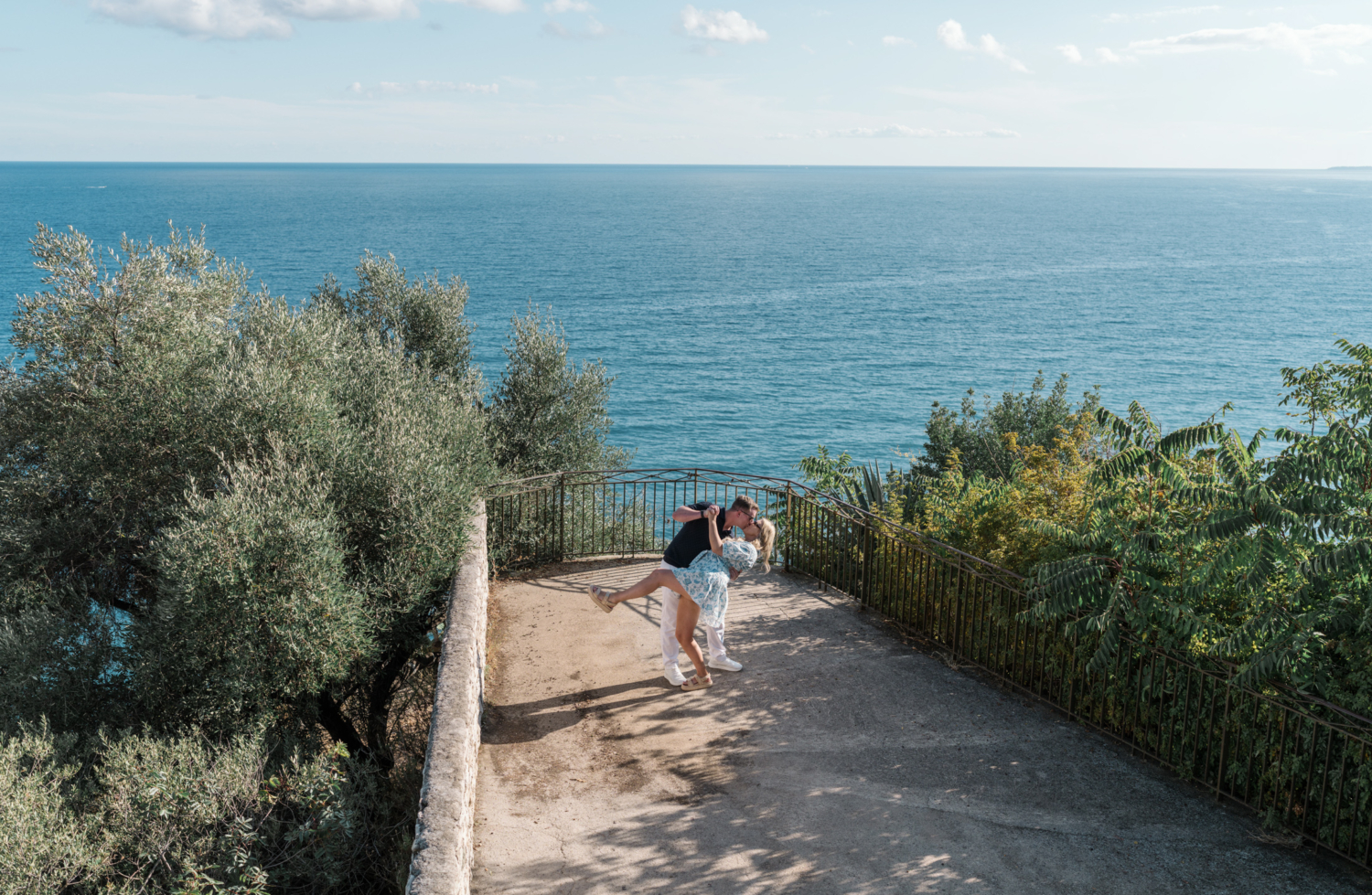 man dips woman backward during enagement photosession with view of sea in nice france