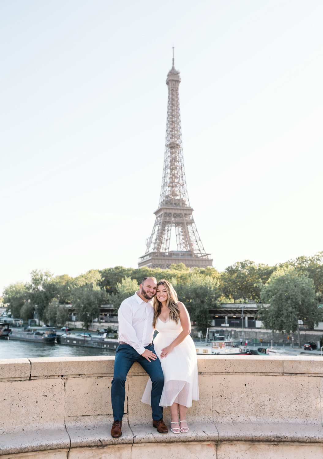 engaged couple smile and touch heads with eiffel tower behind them in paris france