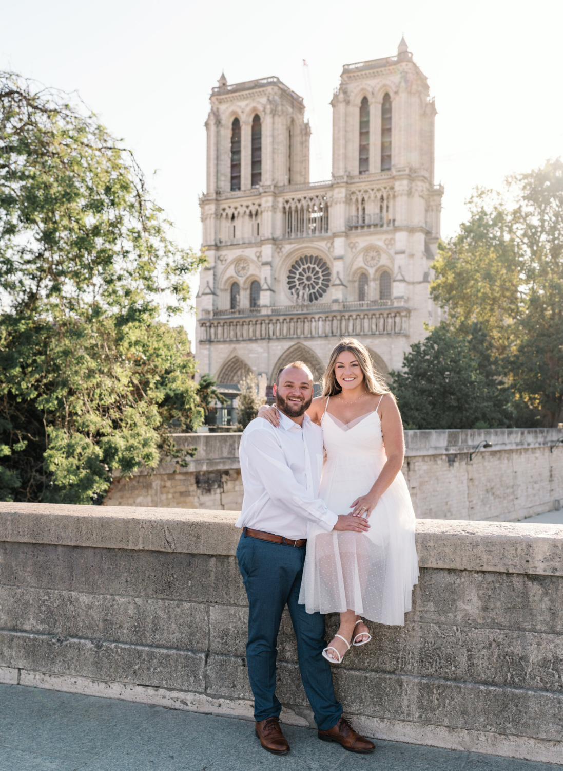 cute engaged couple pose in front of notre dame cathedral in paris france