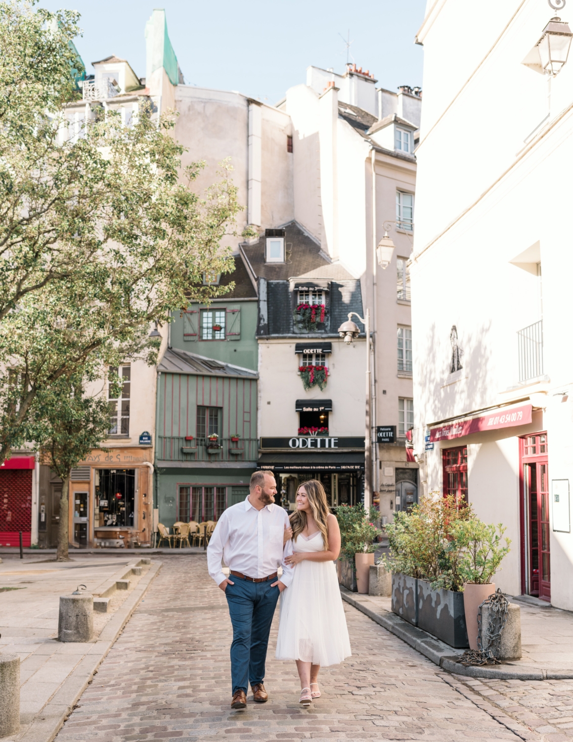 engaged couple smile and walk arm in arm on the left bank in paris france