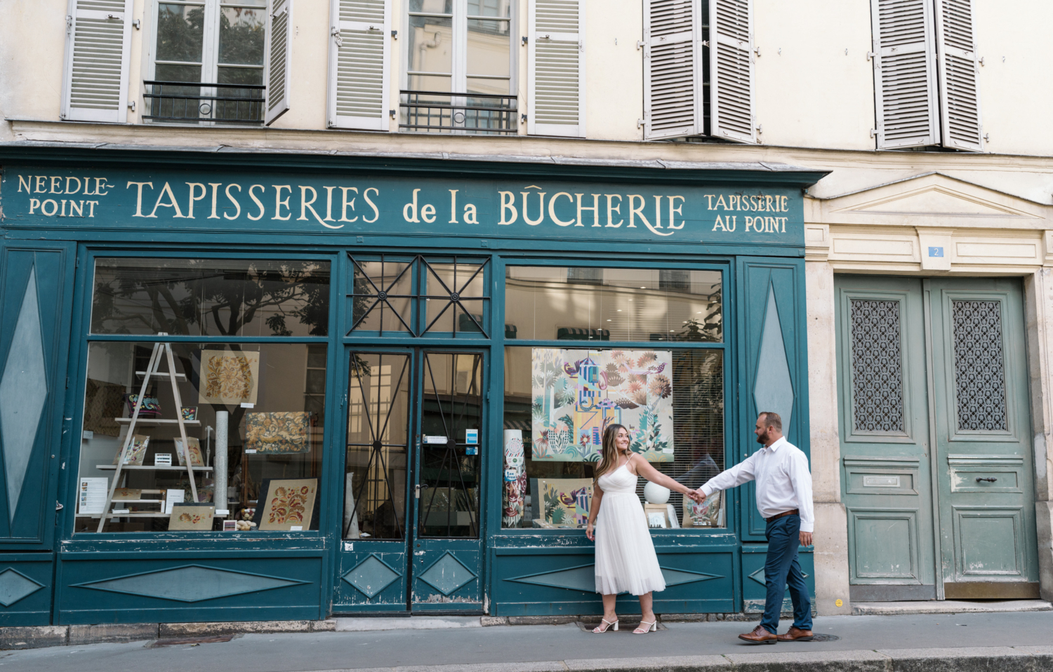 cute couple walk in front of tapestry shop in paris france