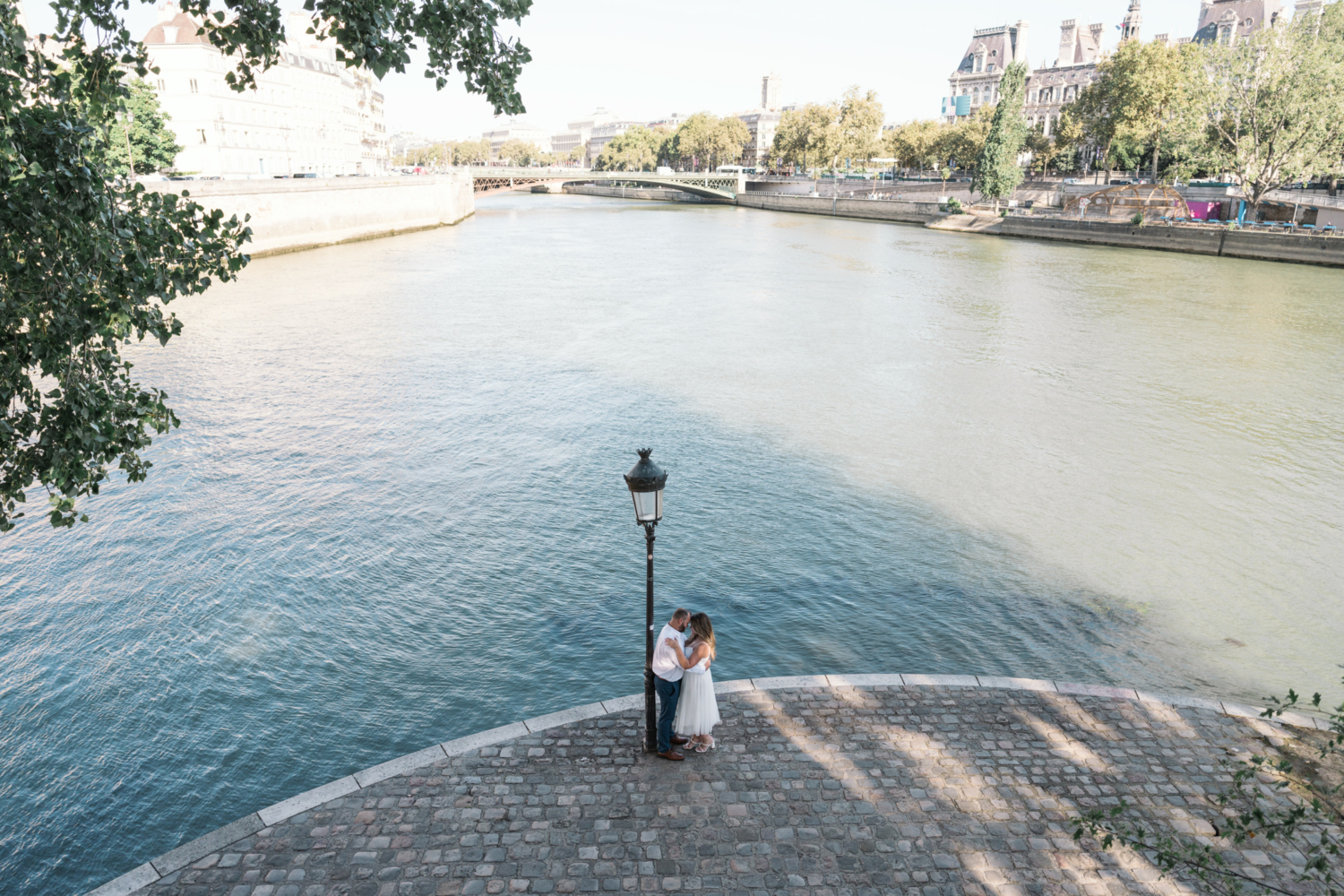 Engaged couple embrace next to seine river in paris france