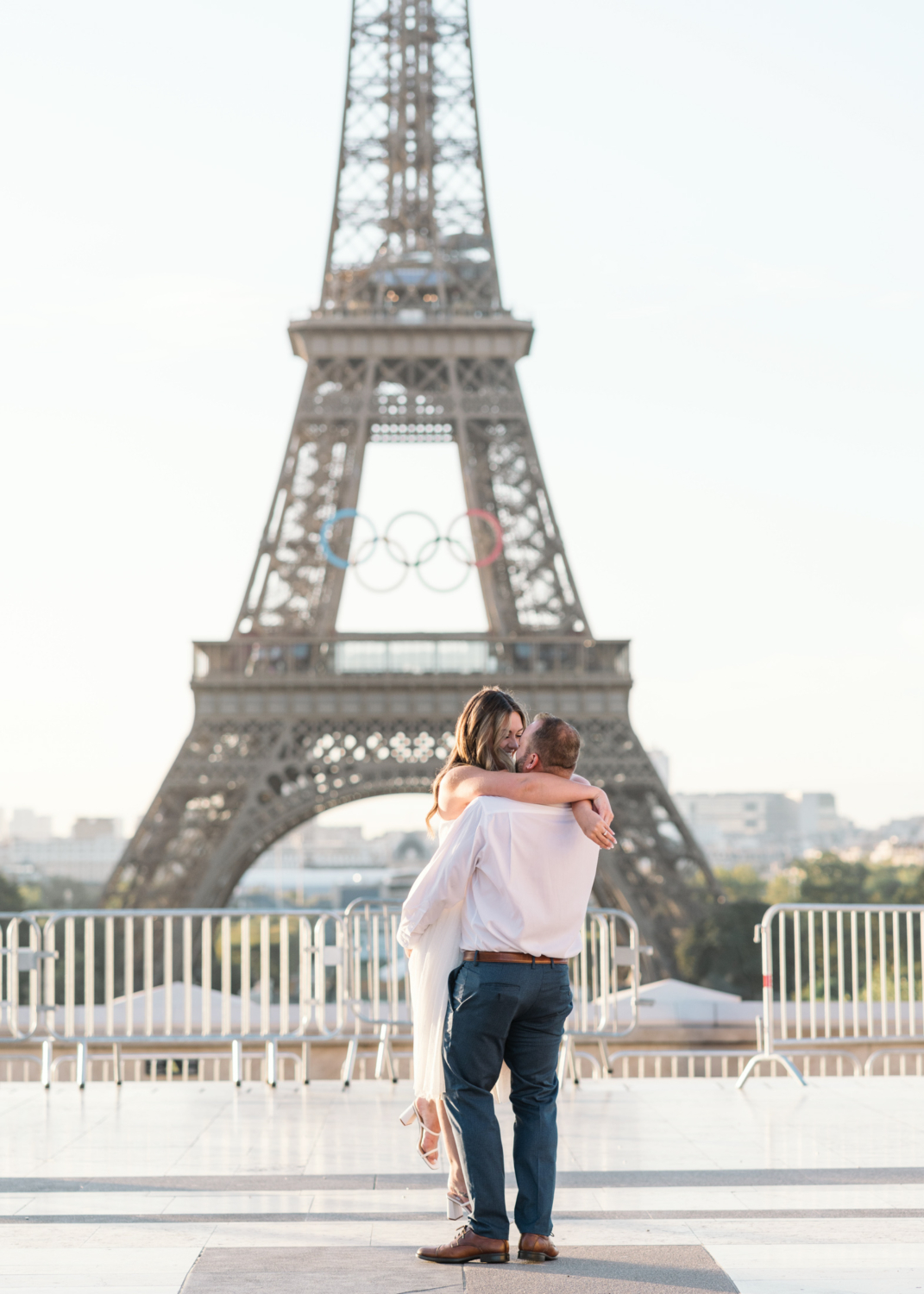 man lifts fiancee and twirls her with view of eiffel tower