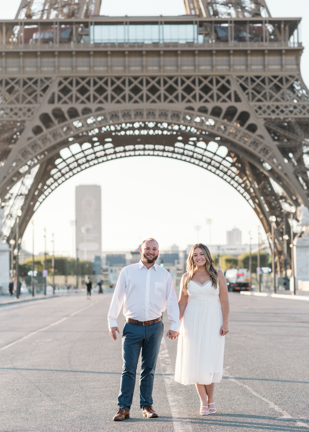 couple dressed in white pose near eiffel tower in paris france