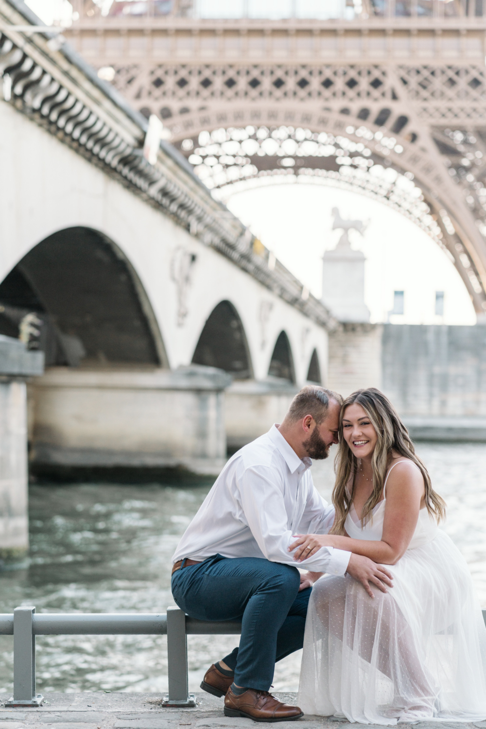 woman smiles as fiancee leans on her with view of eiffel tower