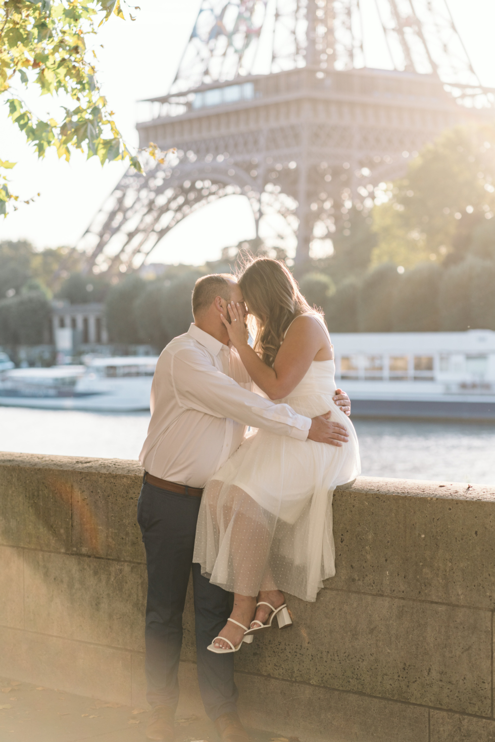 beautiful engaged couple embrace in sun with eiffel tower in background