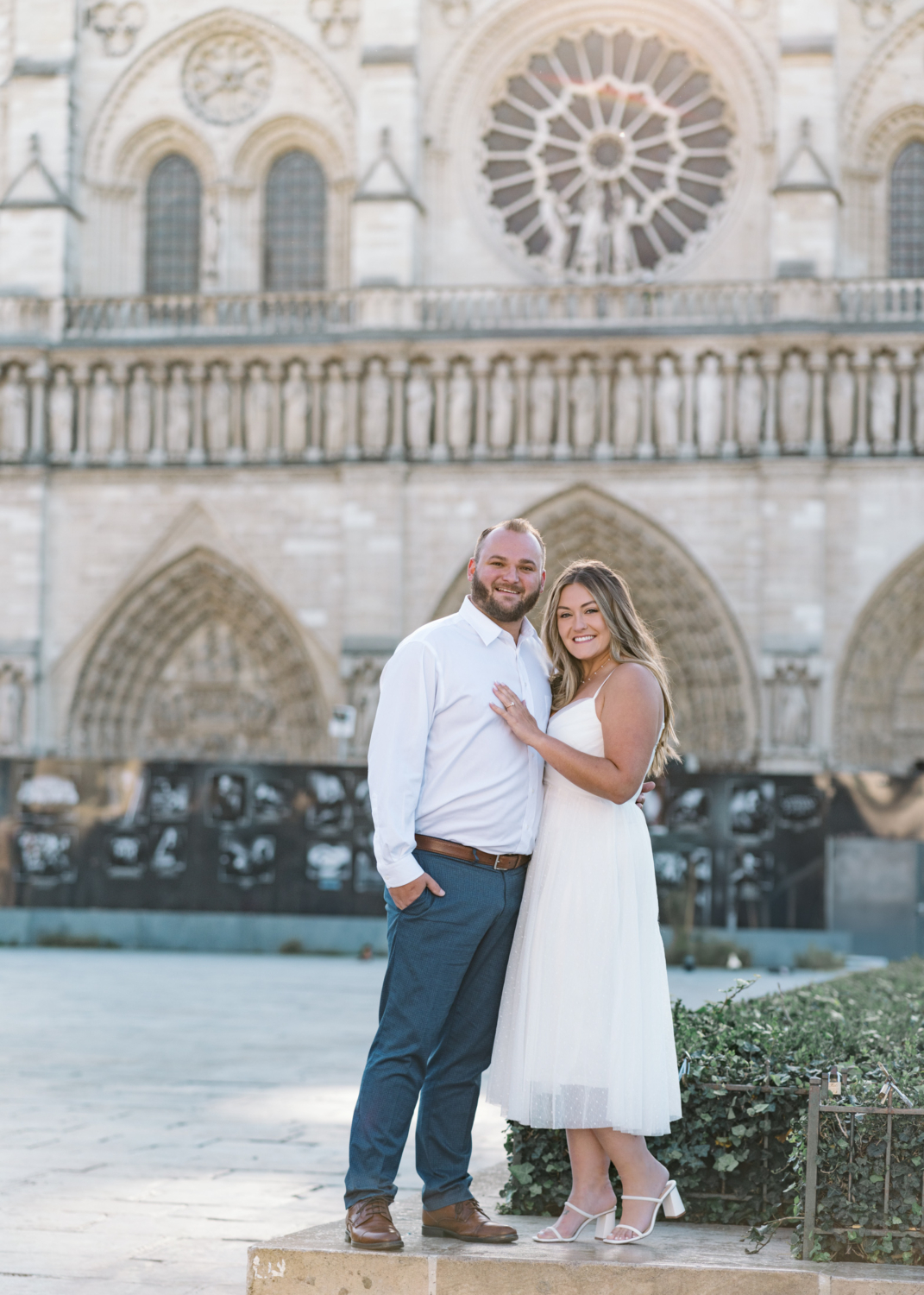 engaged couple pose in front of notre dame cathedral in paris france