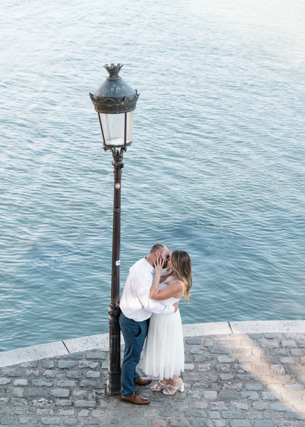 couple kiss passionately next to seine river in paris france