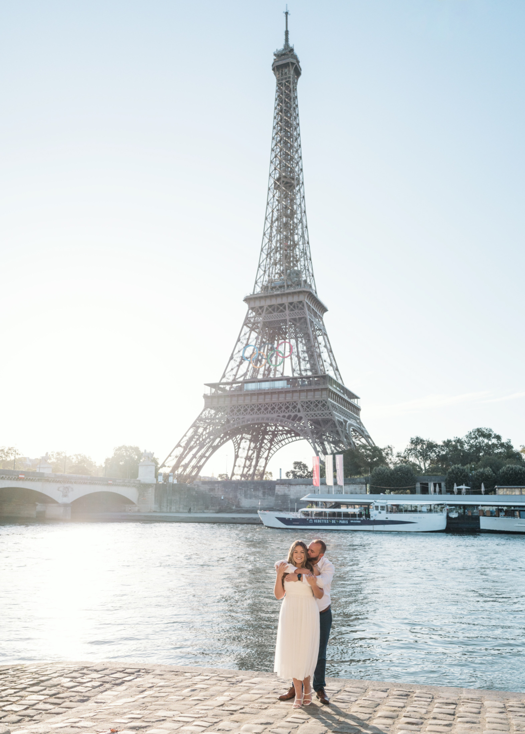 cute couple embrace and smile with eiffel tower behind them