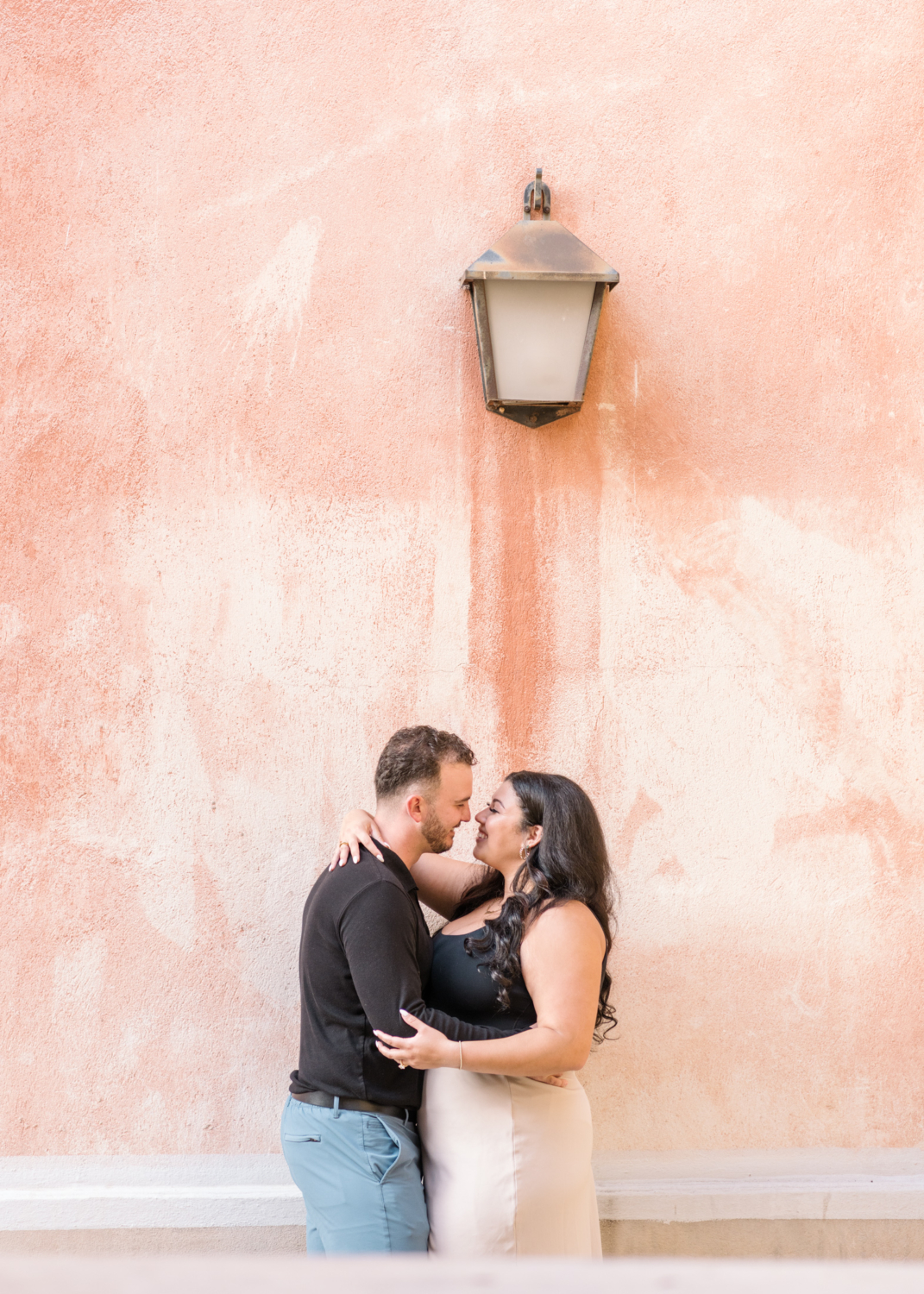 newly engaged couple in nice france hold each other in front of orange wall