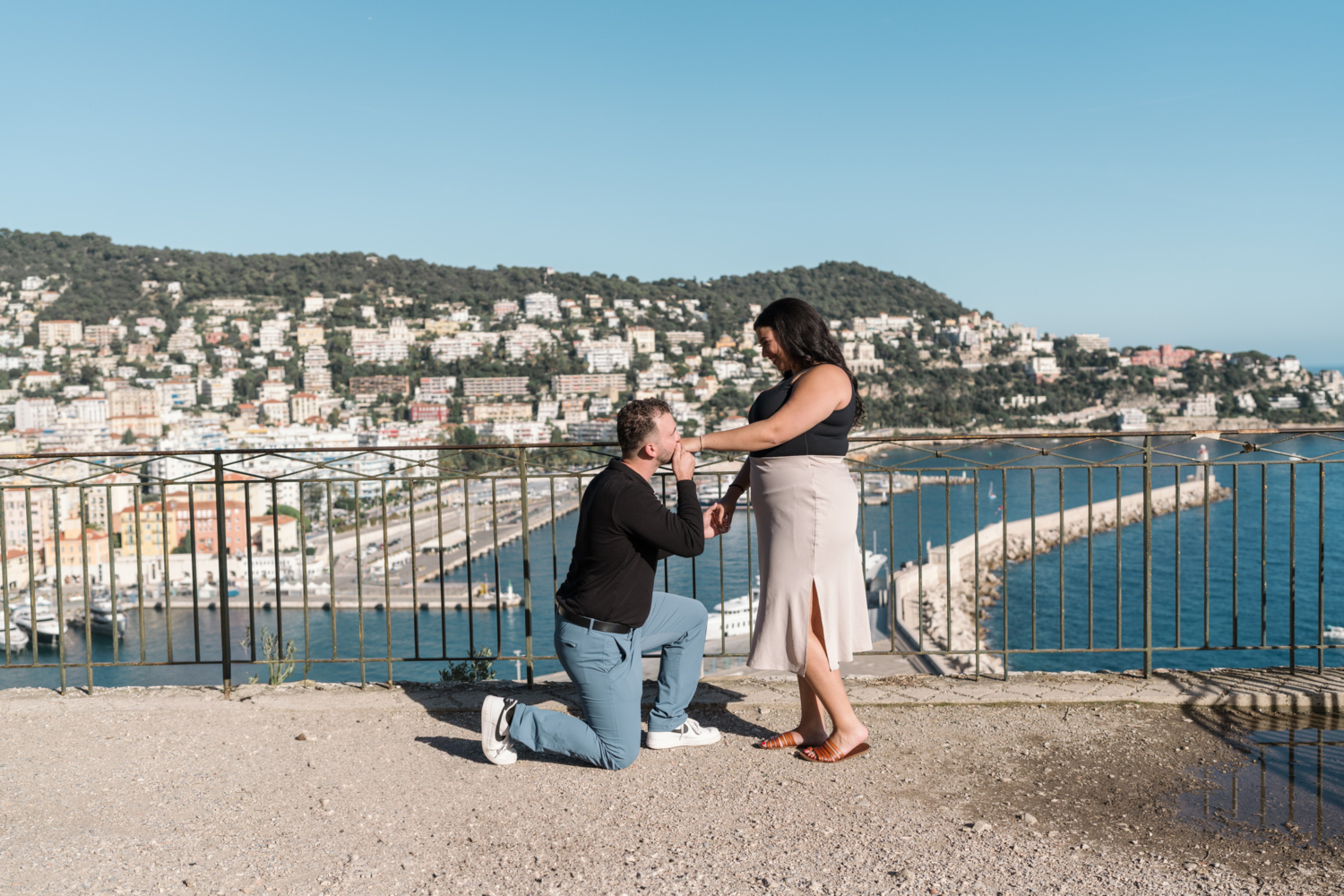 man kisses new fiance's hand with view of blue sea in old town nice france