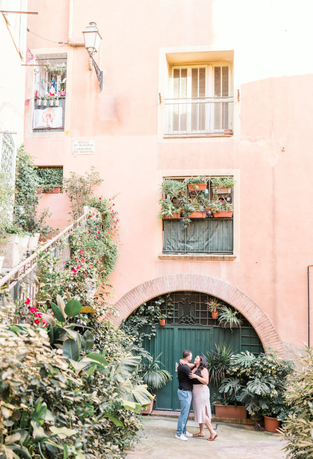 newly engaged couple embrace in front of green door in nice france