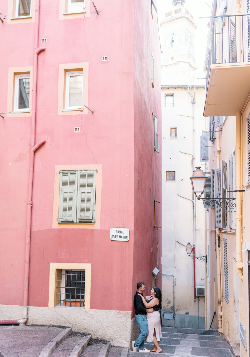 newly engaged couple embrace in old town next to orange building in nice france