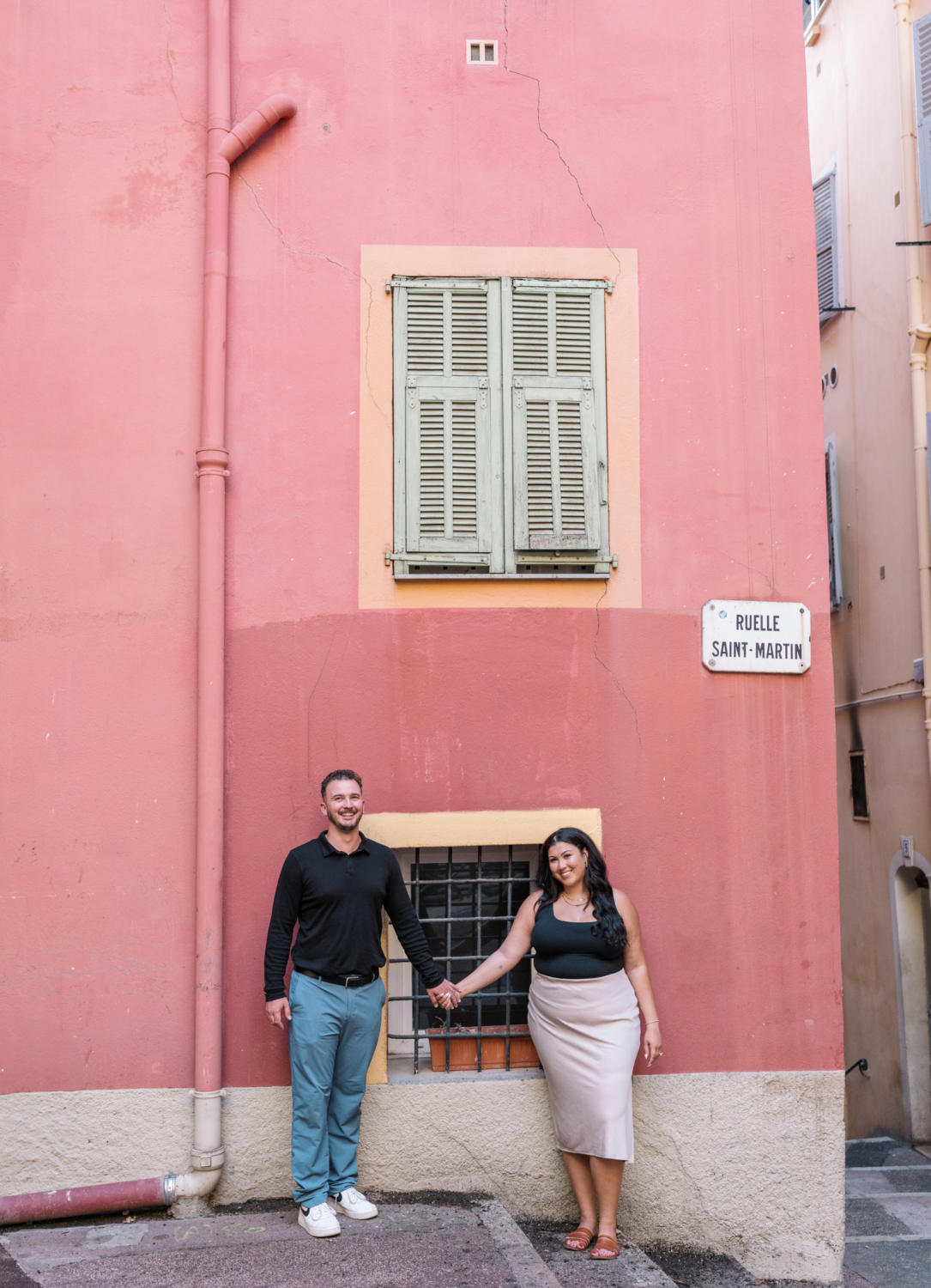 newly engaged couple smile next to colorful building in nice france