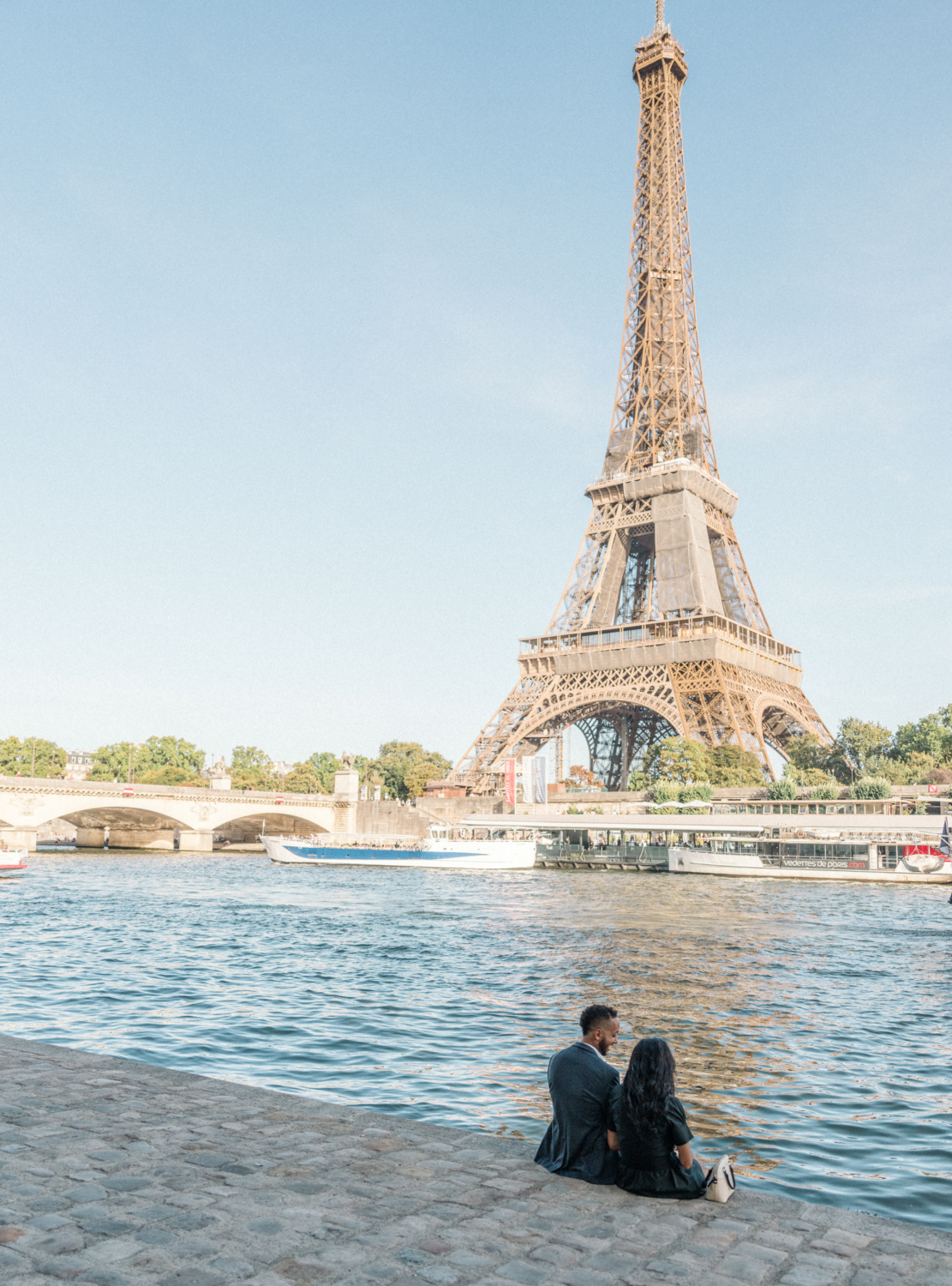 newly engaged african american couple sit at the eiffel tower