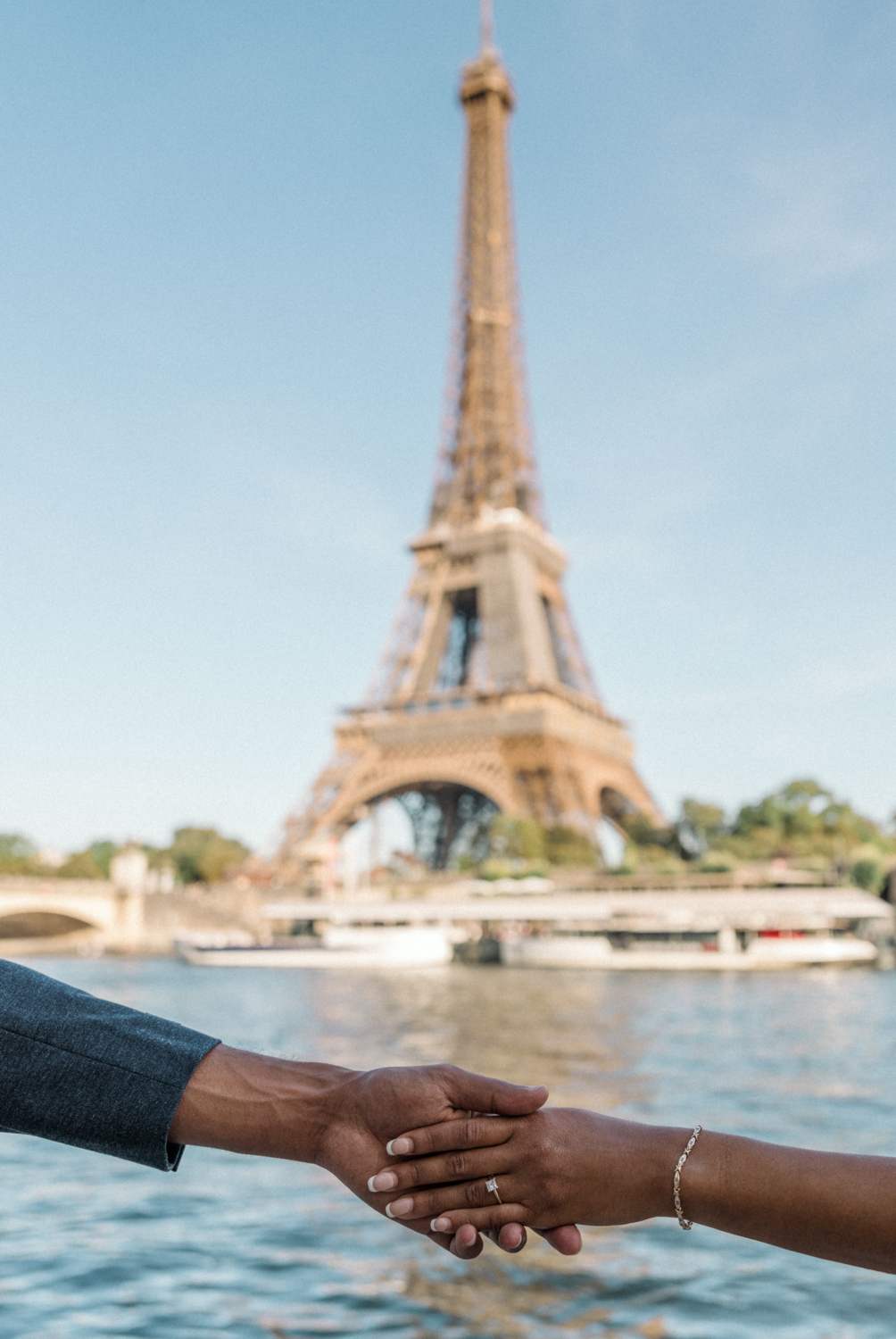 newly engaged african american couple hold hands with diamond ring at the eiffel tower