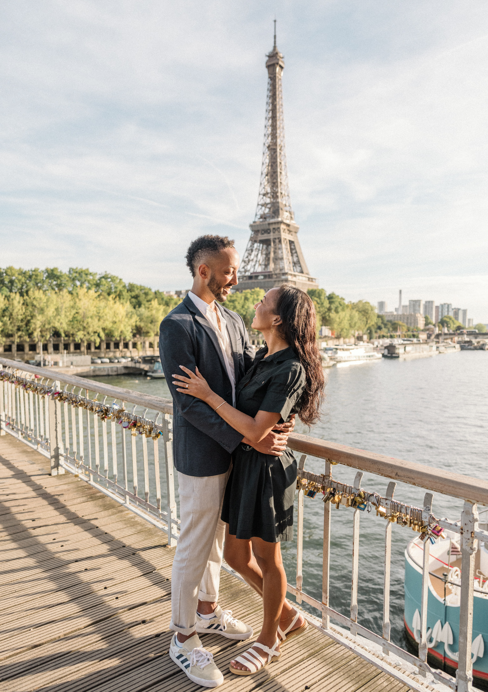 newly engaged african american couple embrace on bridge with view of eiffel tower in paris