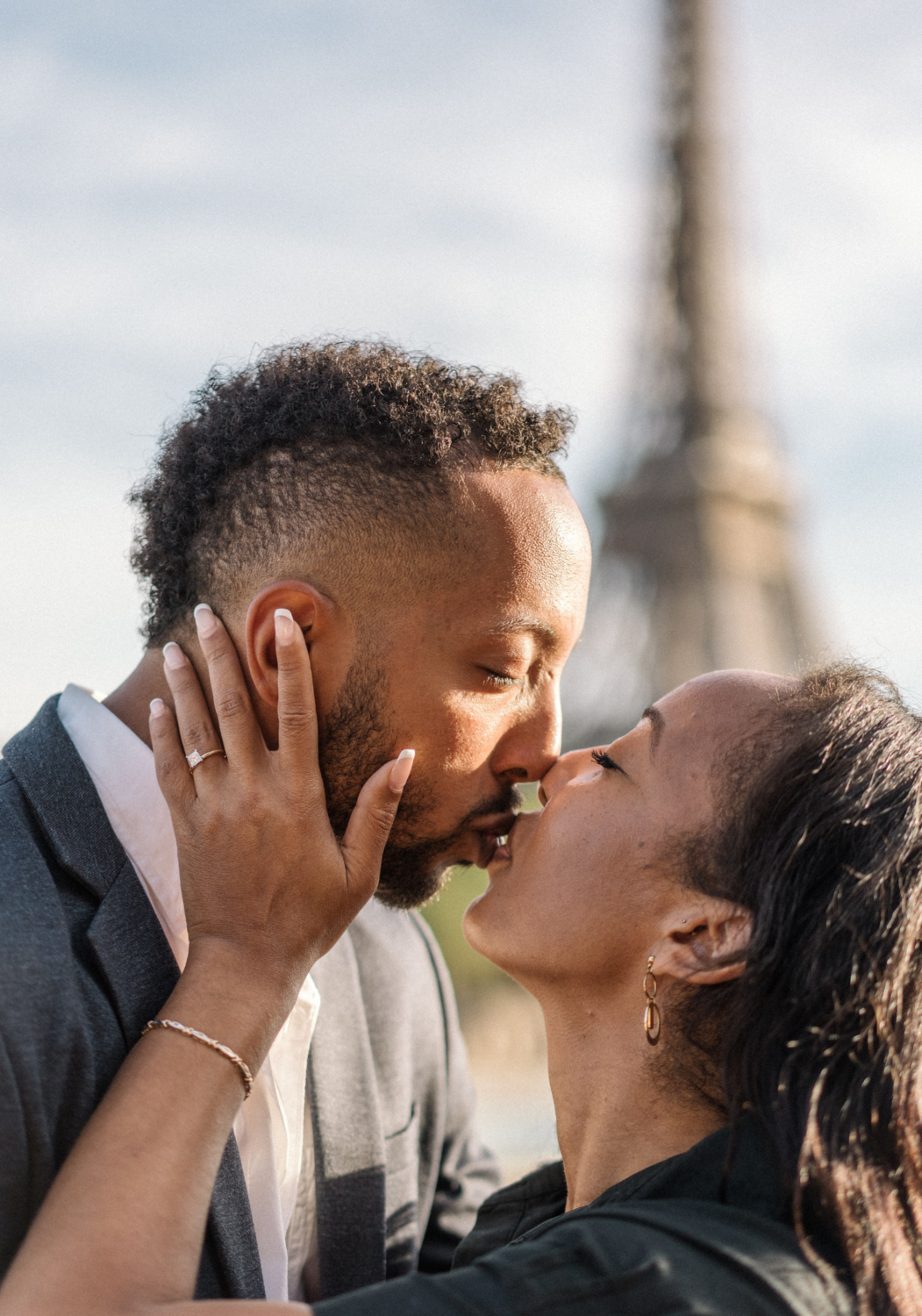 newly engaged african american couple kiss with view of the eiffel tower