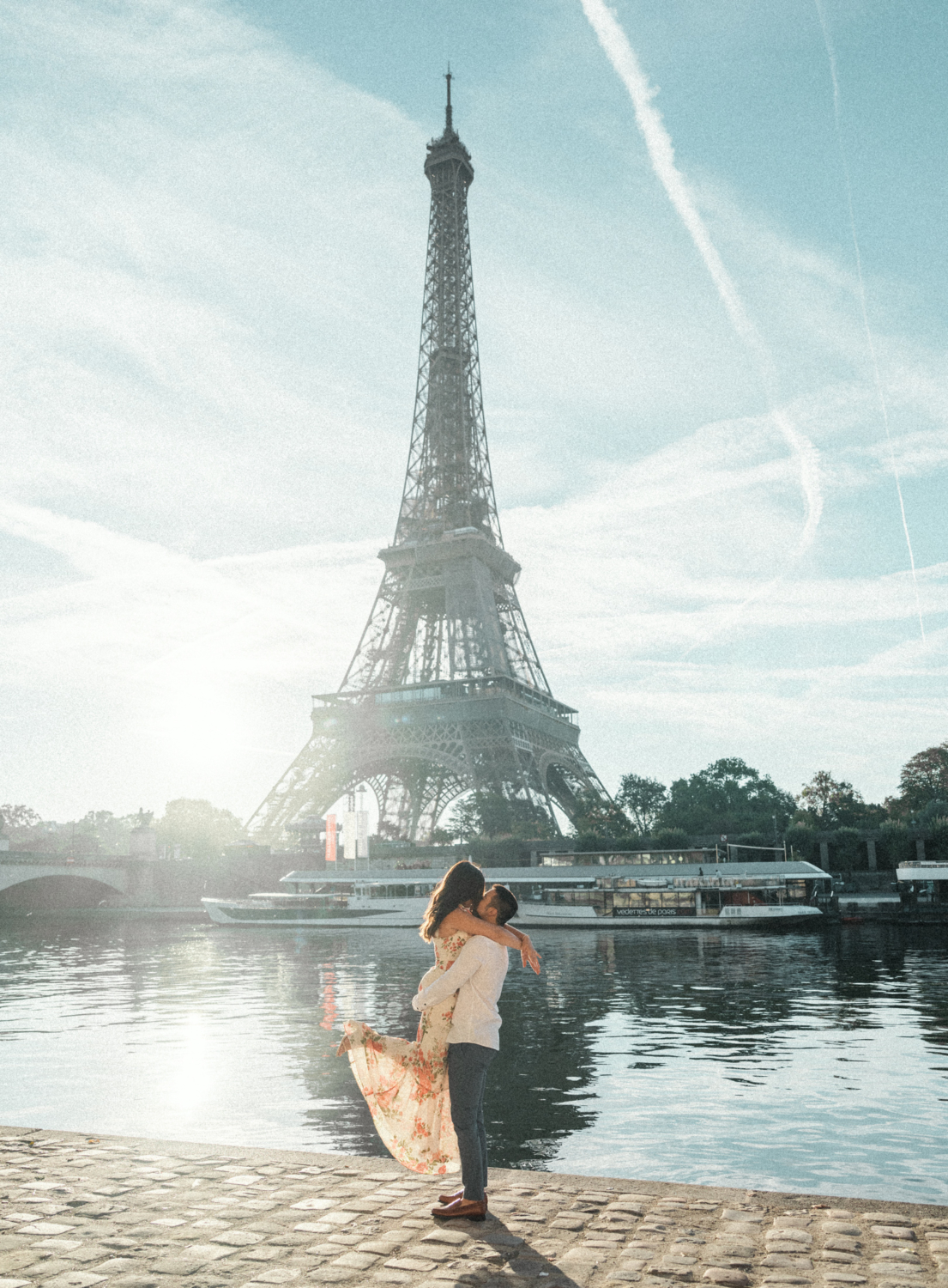 man lifts woman in air with view of eiffel tower in background