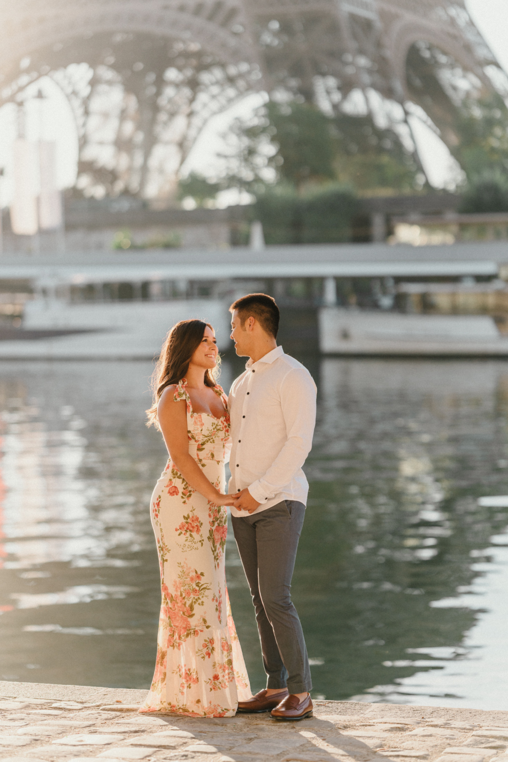 happy engaged couple look at each other in the sunshine in paris