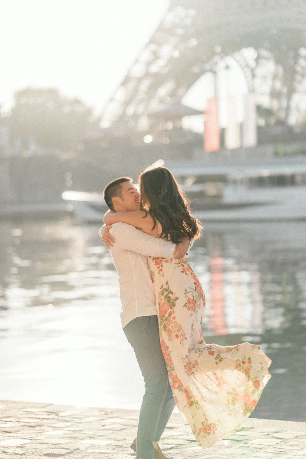 man lifts woman in the sunlight with the eiffel tower in the background