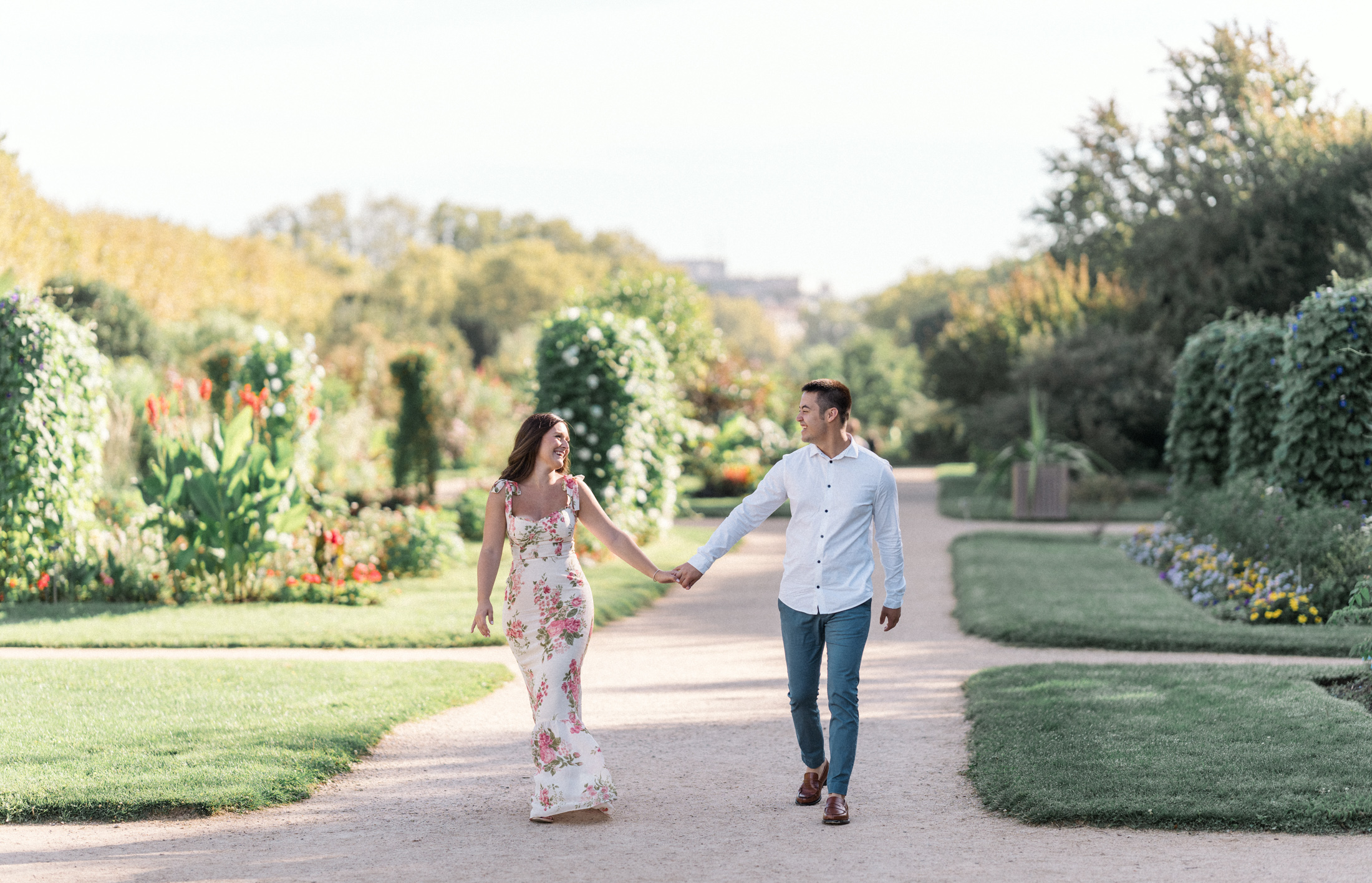 happy couple laugh and walk through jardin des plantes in paris france