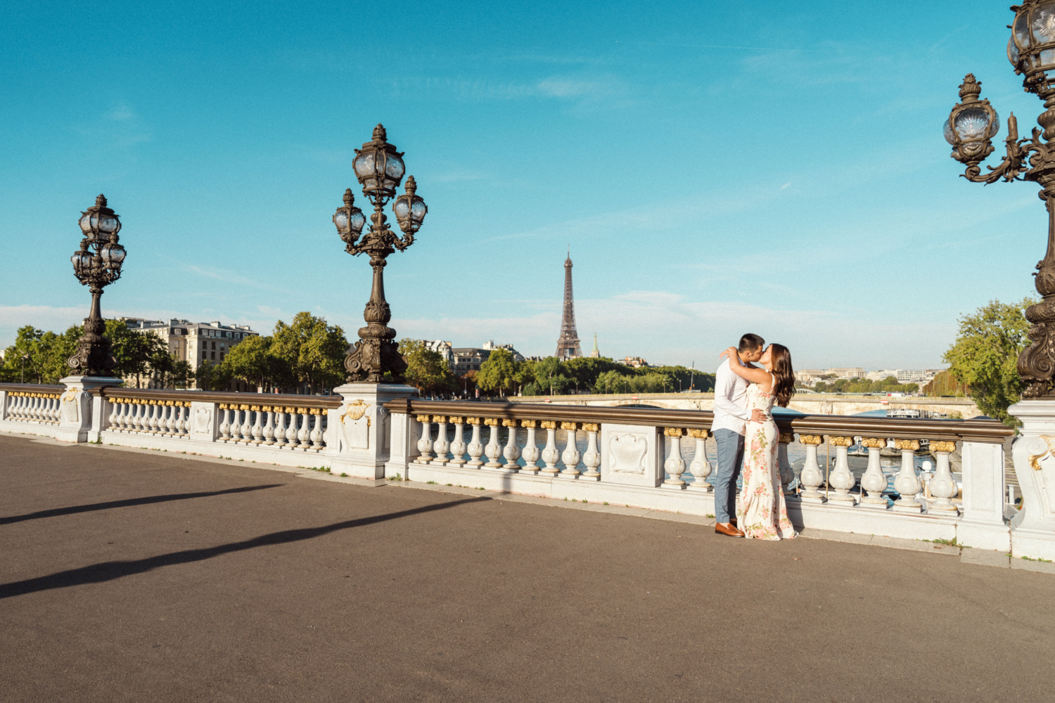 engaged couple kiss passionately on pont alexandre with view of eiffel tower