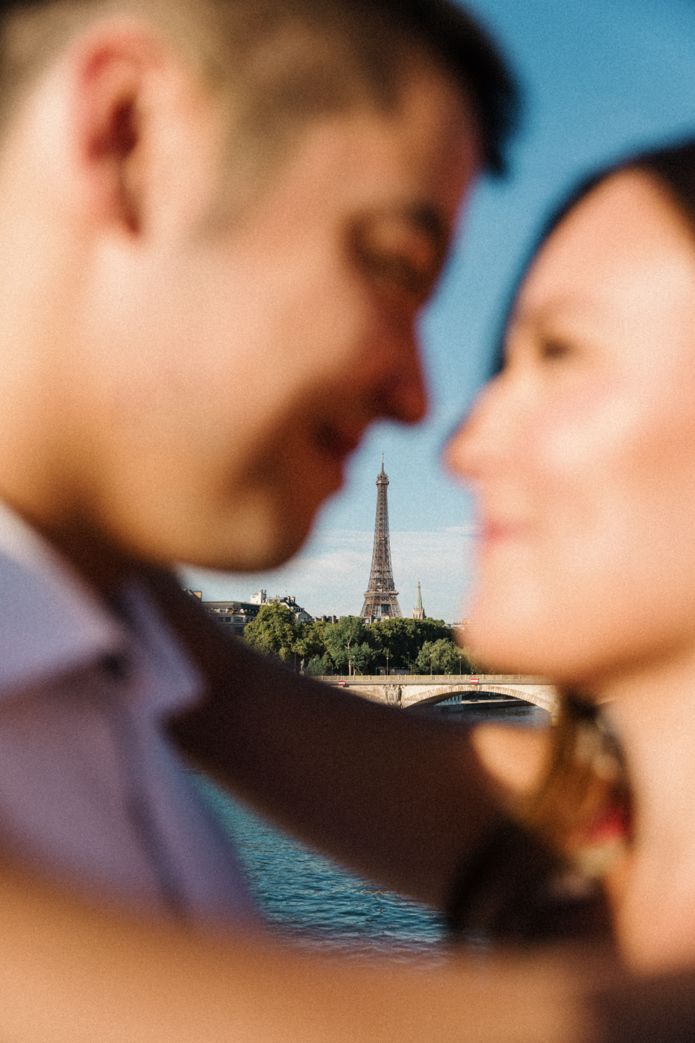 view of the eiffel tower in between the nose of a couple in paris