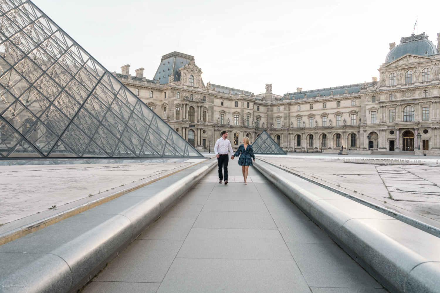 young newly engaged couple walk happily at the louvre courtyard in paris france