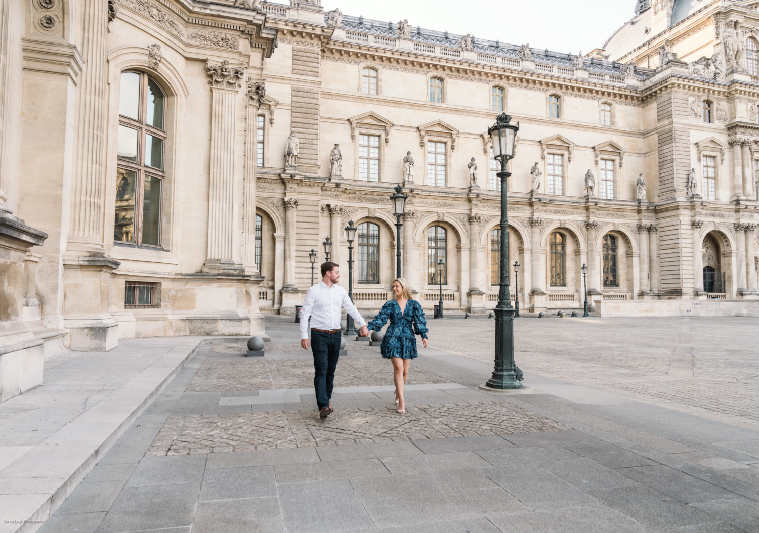 young newly engaged couple walk at the louvre museum in paris