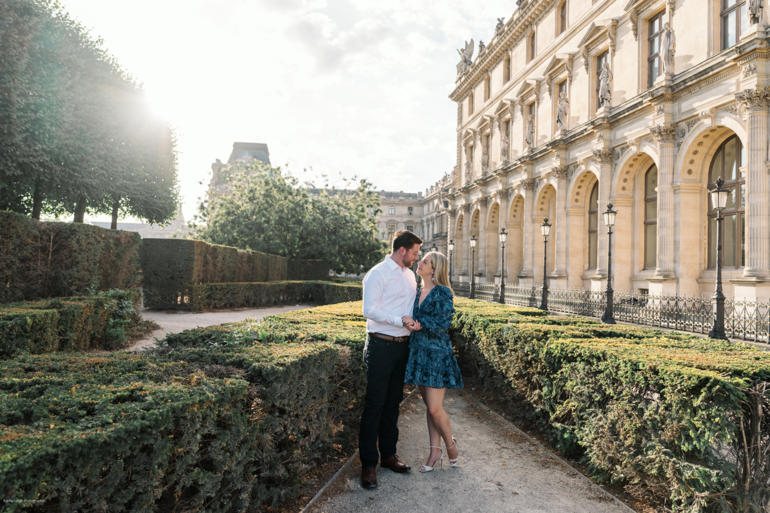 young newly engaged couple embrace near the louvre museum in paris