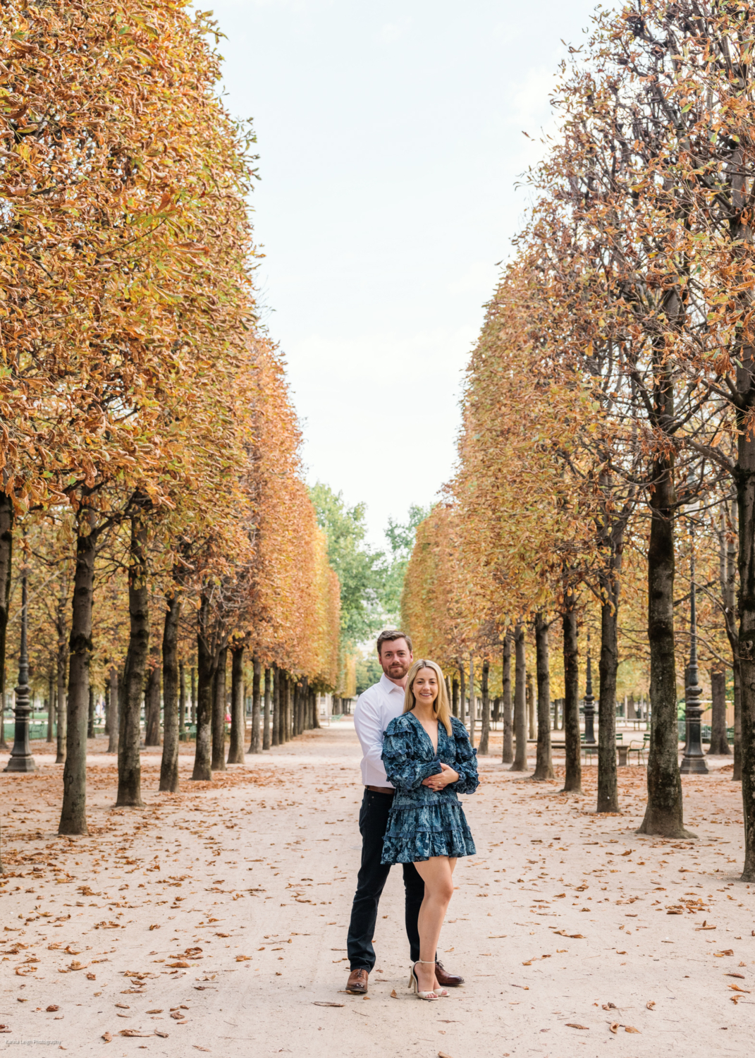 young newly engaged couple pose during autumn in the tuileries gardens in paris