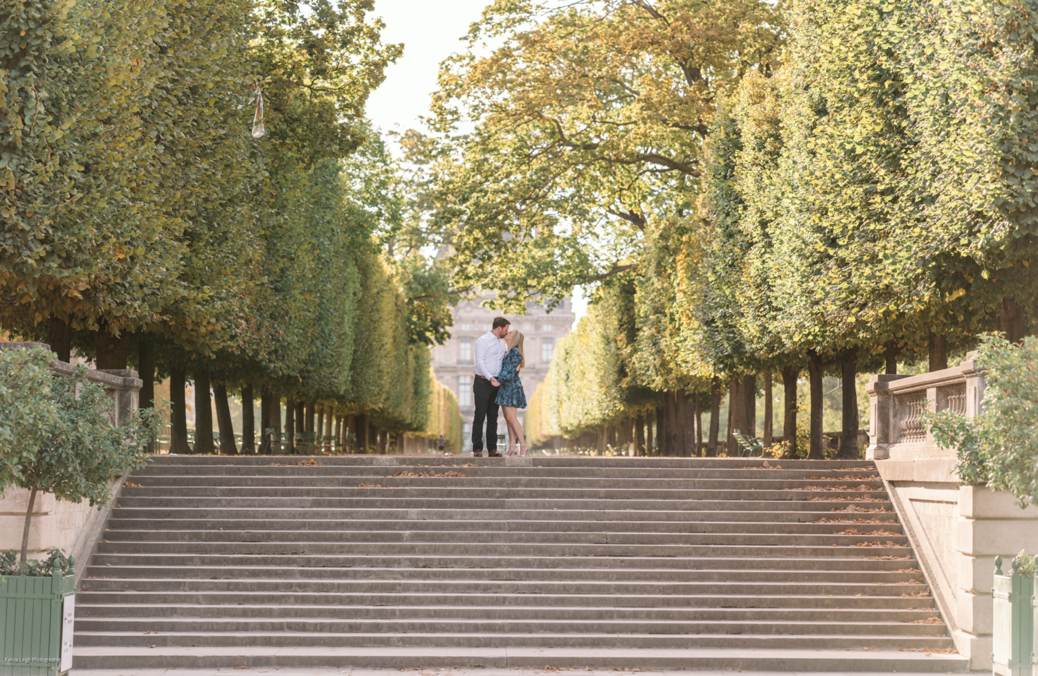 young newly engaged couple kiss during engagement photoshoot in paris in tuileries gardens