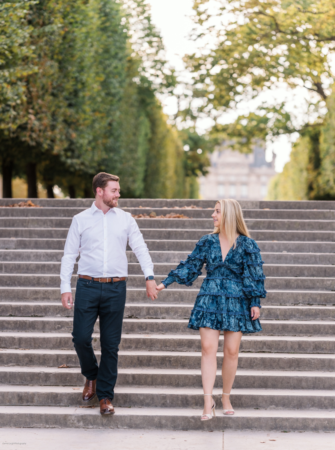 young newly engaged couple walk down staircase in tuileries gardens in paris