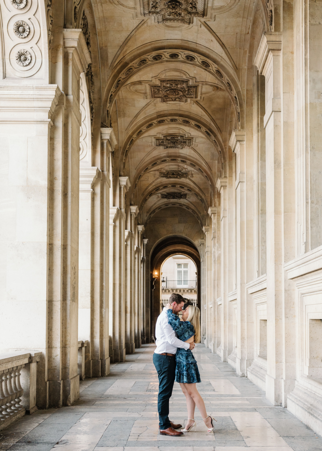 young newly engaged couple hold each other at the louvre museum in paris