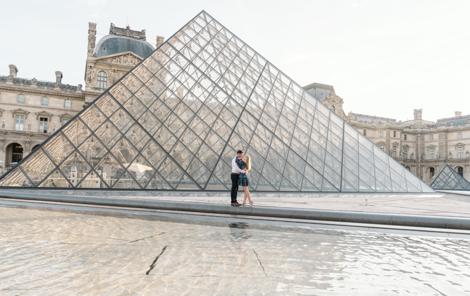 young newly engaged couple engage at the glass pyramid in paris