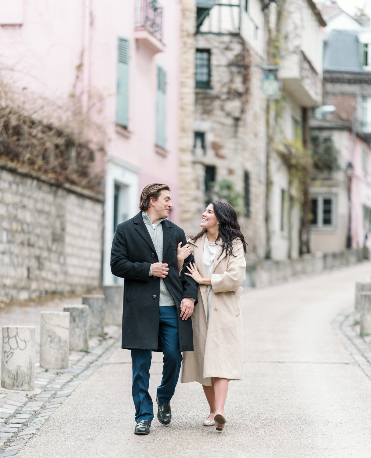 newly engaged couple walk arm in arm in colorful neighborhood in paris