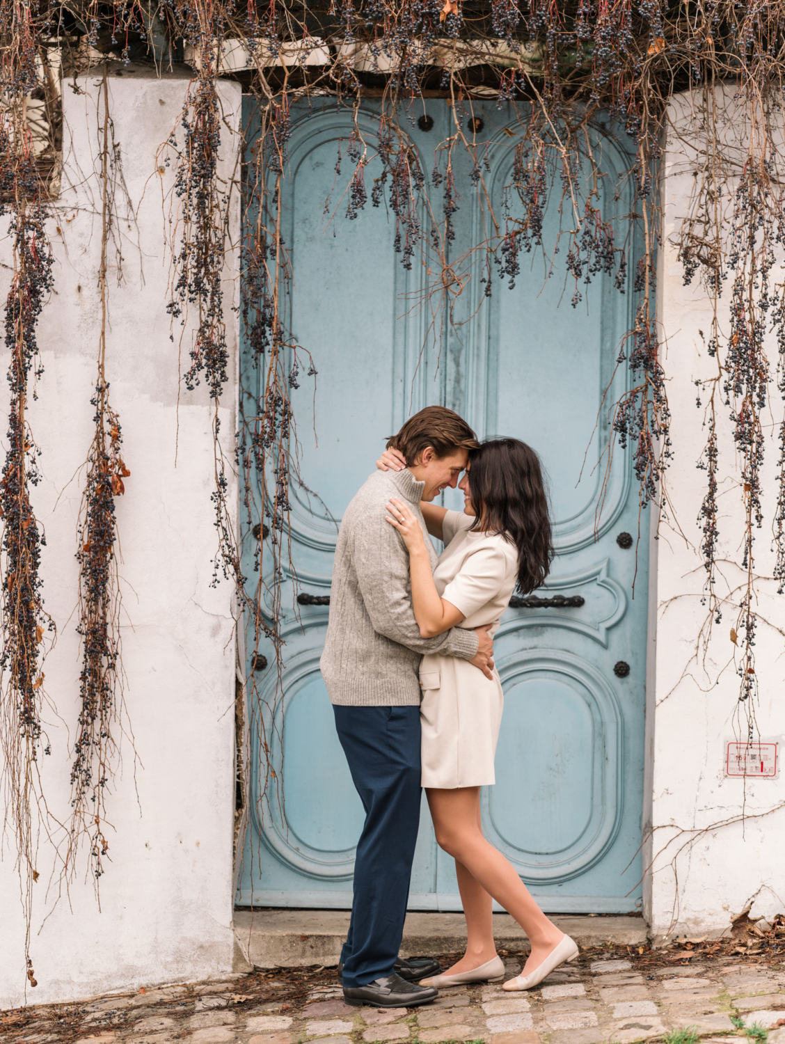 newly engaged couple pose in front of blue door in paris france