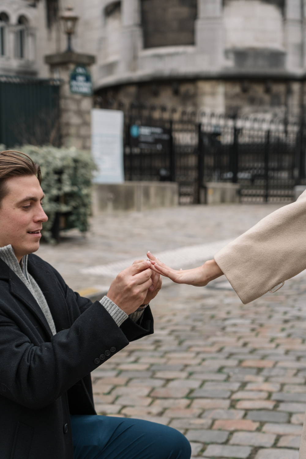 man puts engagement ring on woman's finger in paris france