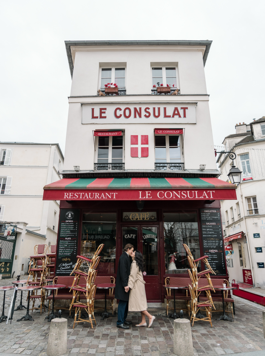 newly engaged couple kiss passionately in front of charming cafe in montmartre paris