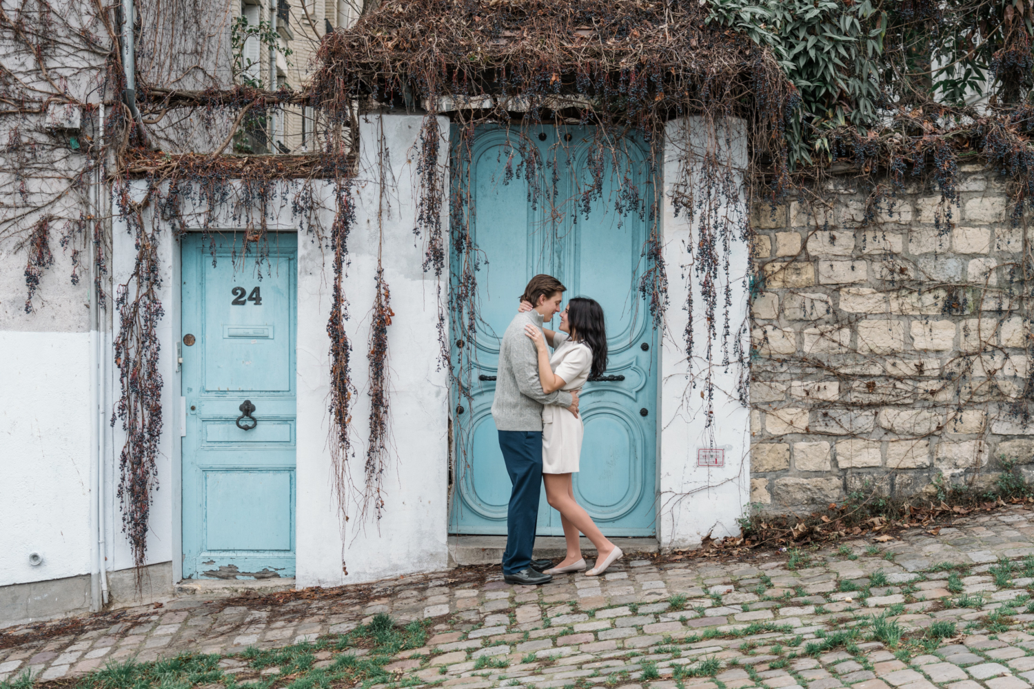 newly engaged couple embrace in front of blue door in montmartre paris france