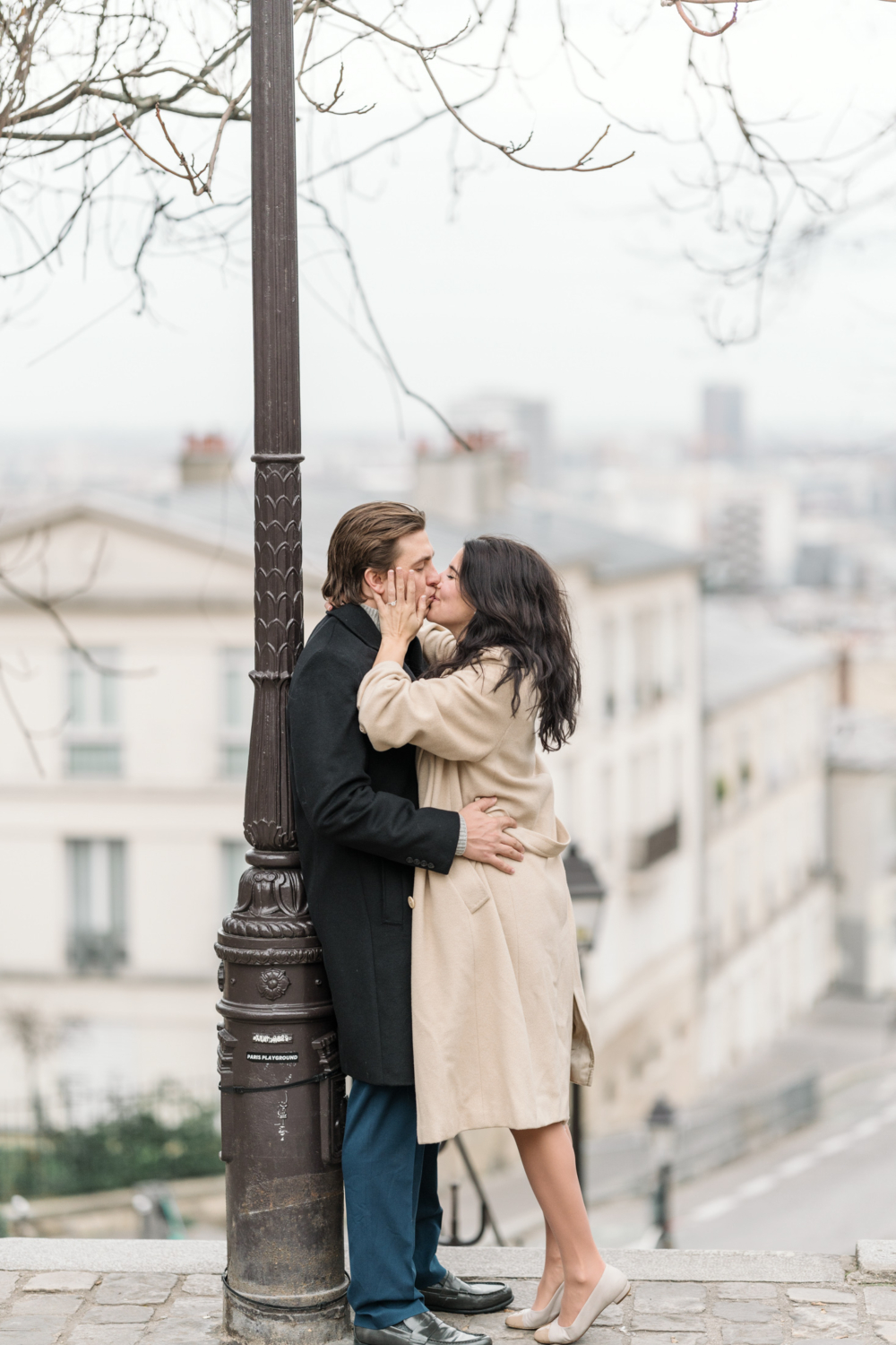 newly engaged couple kiss in charming montmartre neighborhood in paris