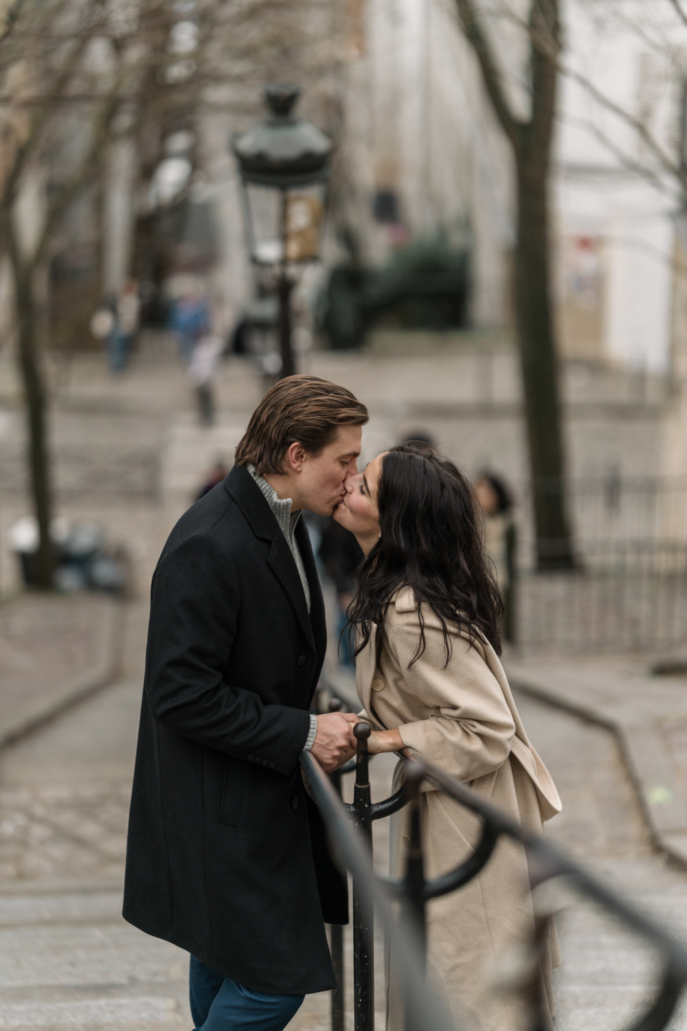 newly engaged couple kiss passionately on staircase in montmartre paris