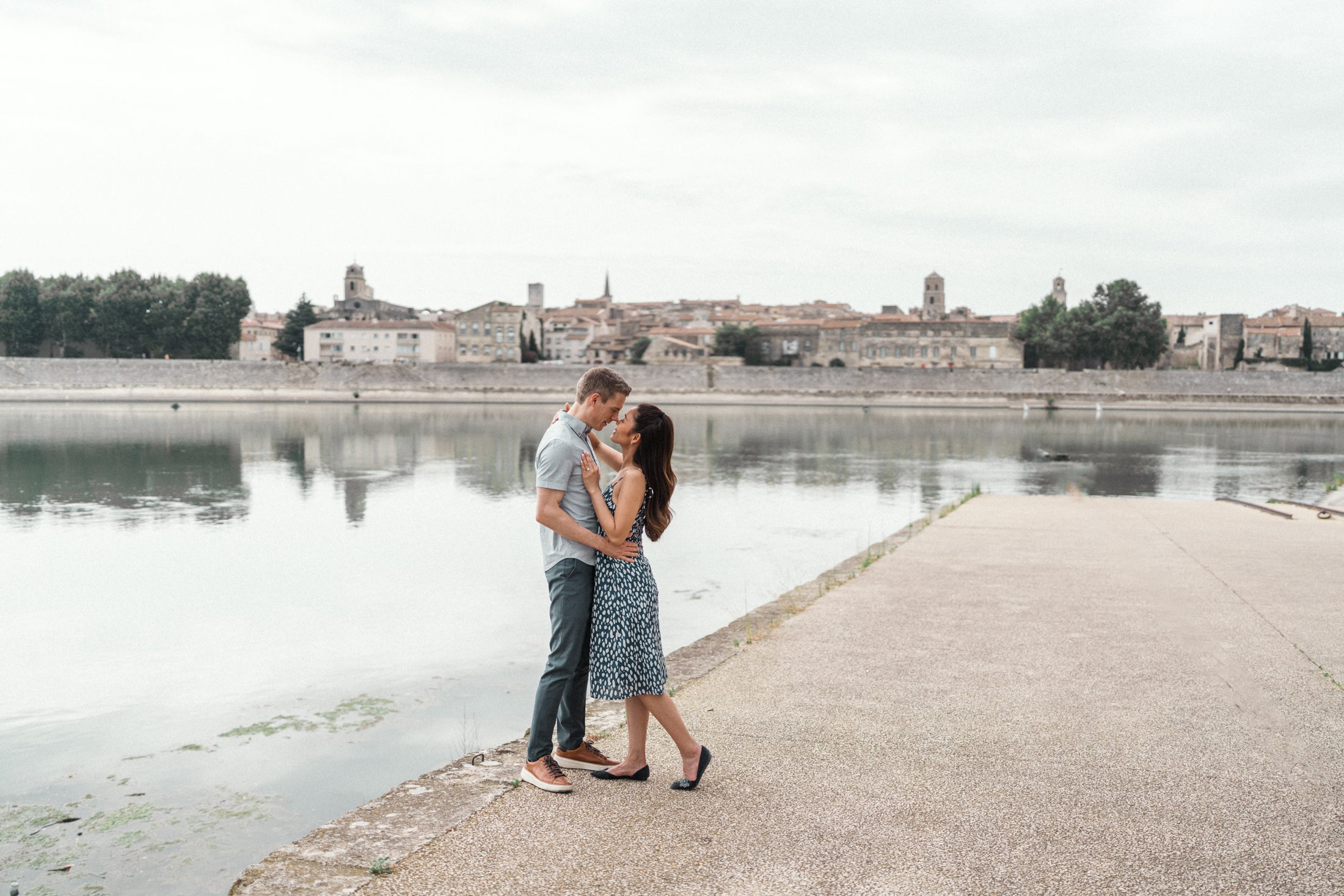 young engaged couple embrace with view of rhone river during Engagement Photos In Provence