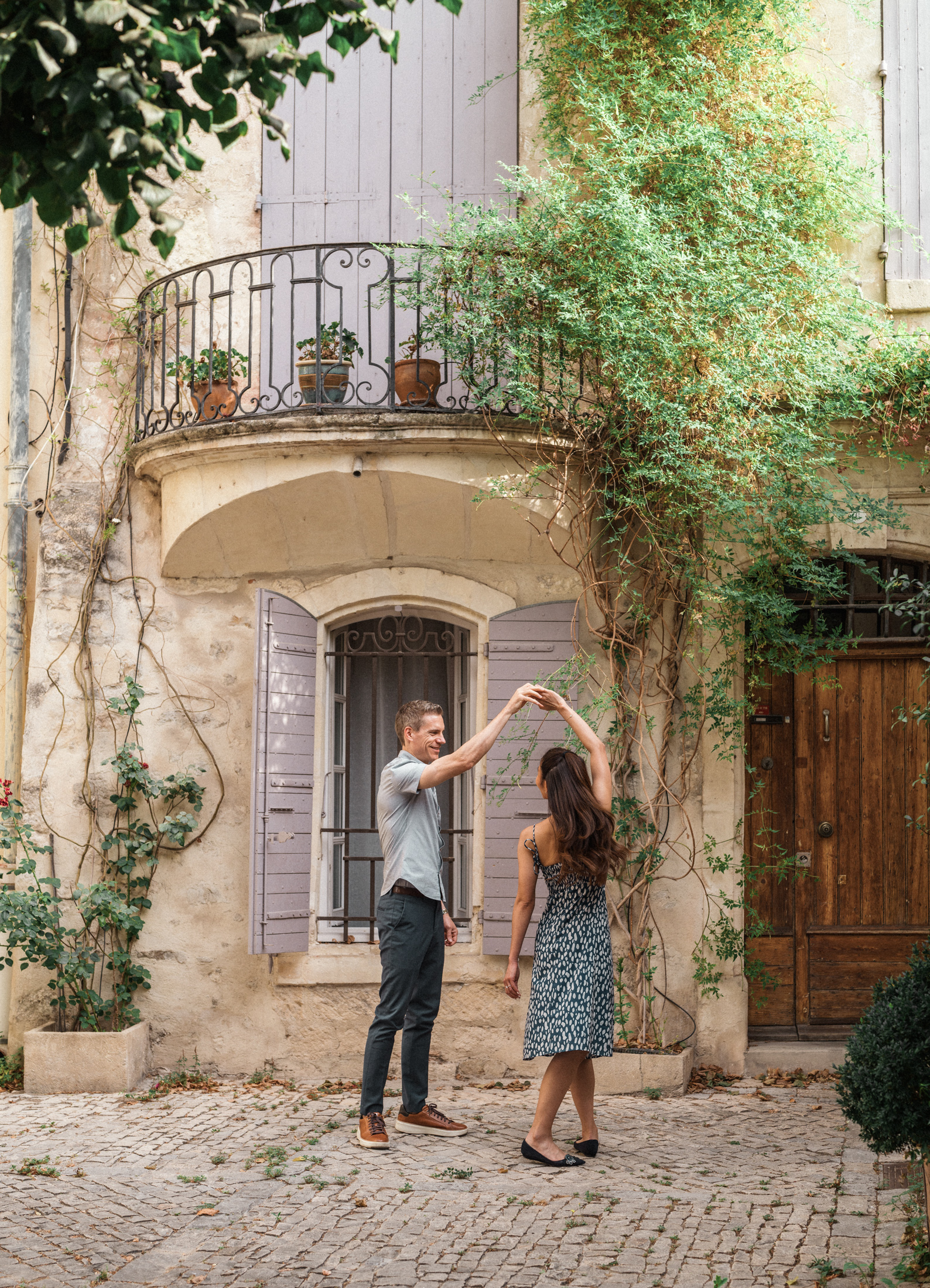 young engaged couple dance in front of house with purple shutters in arles france during Engagement Photos In Provence