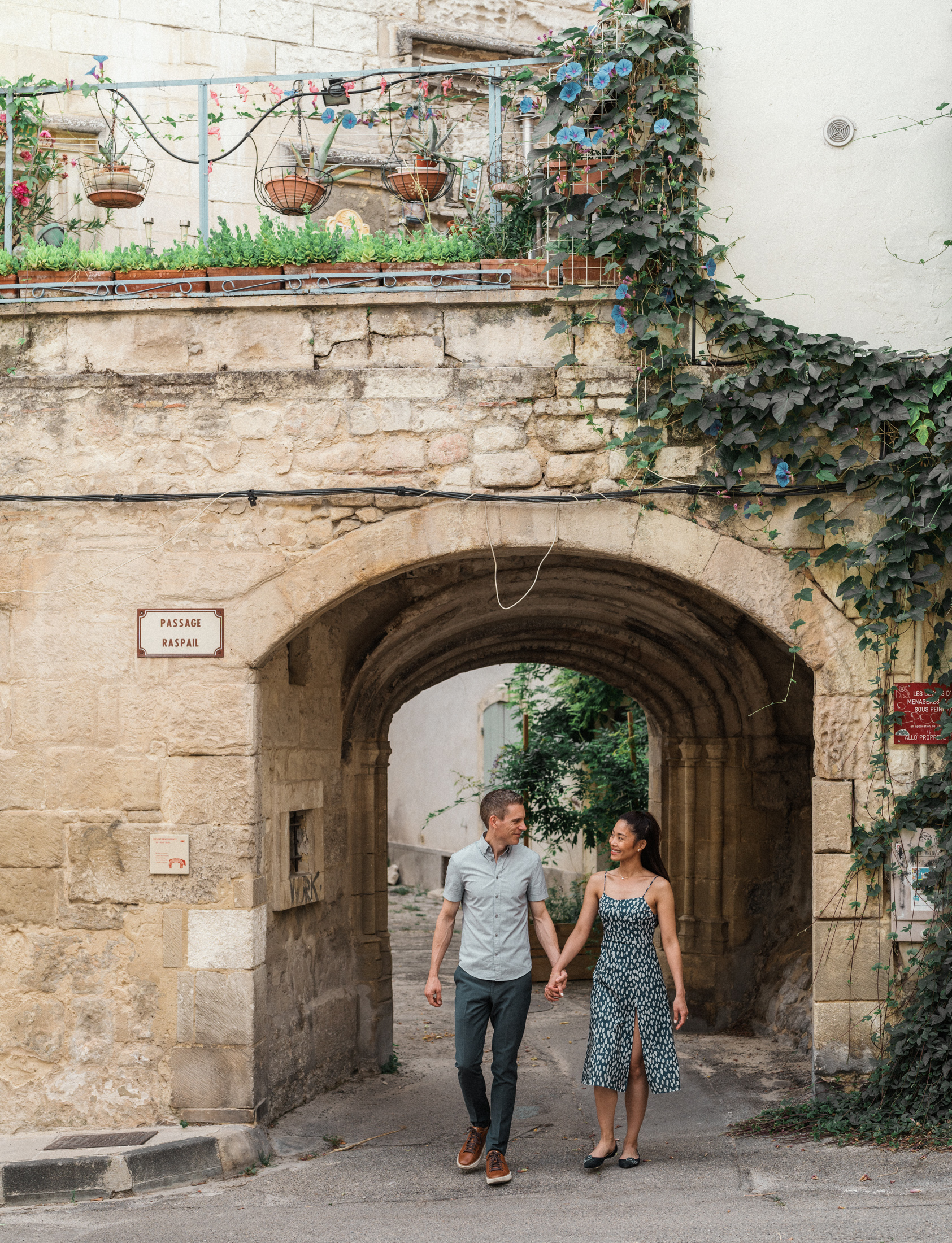 young engaged couple walk through ancient passage in arles france during Engagement Photos In Provence