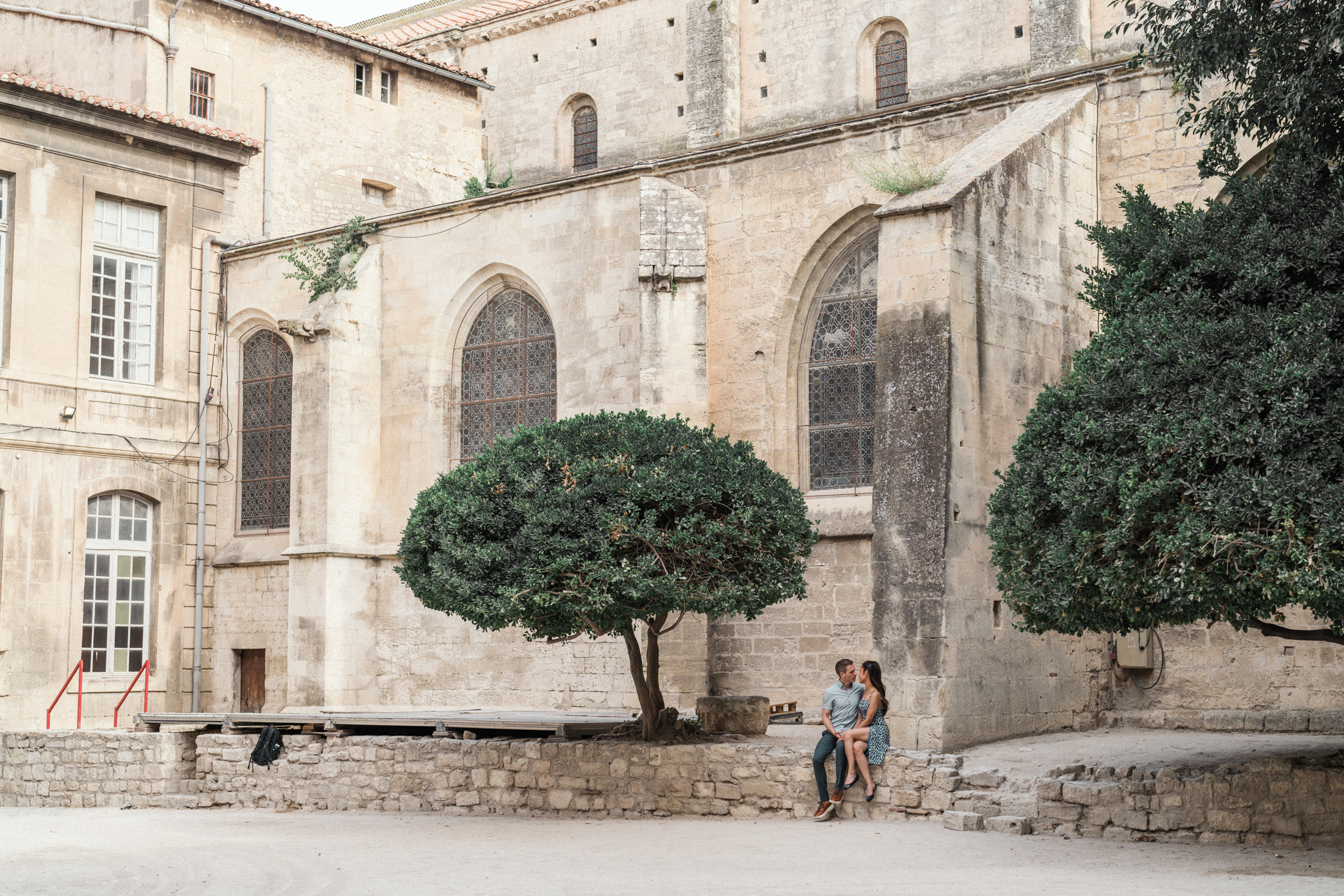 young engaged couple sit outside saint trophime church in arles france during Engagement Photos In Provence