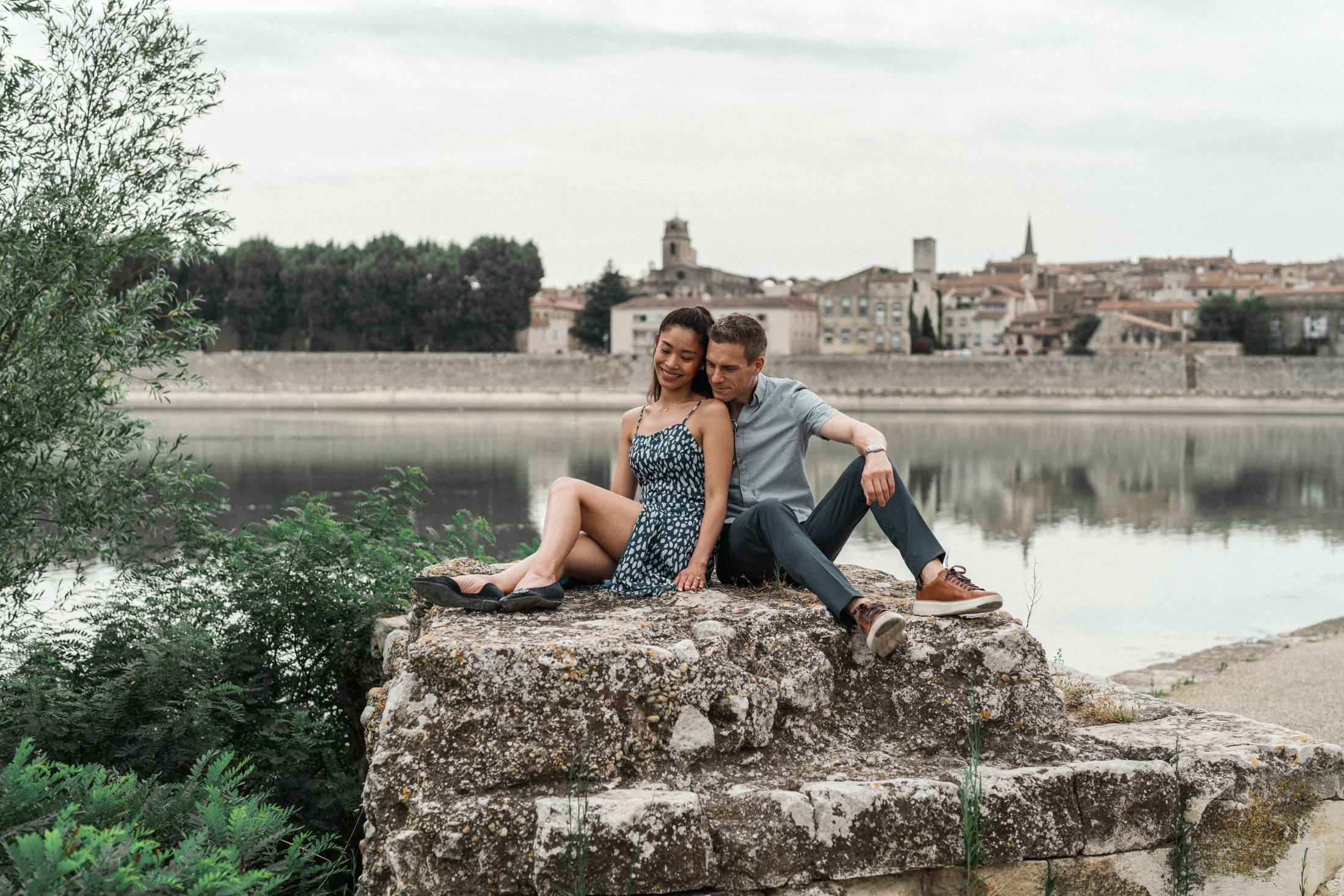 young engaged couple sit on a rock overlooking arles france