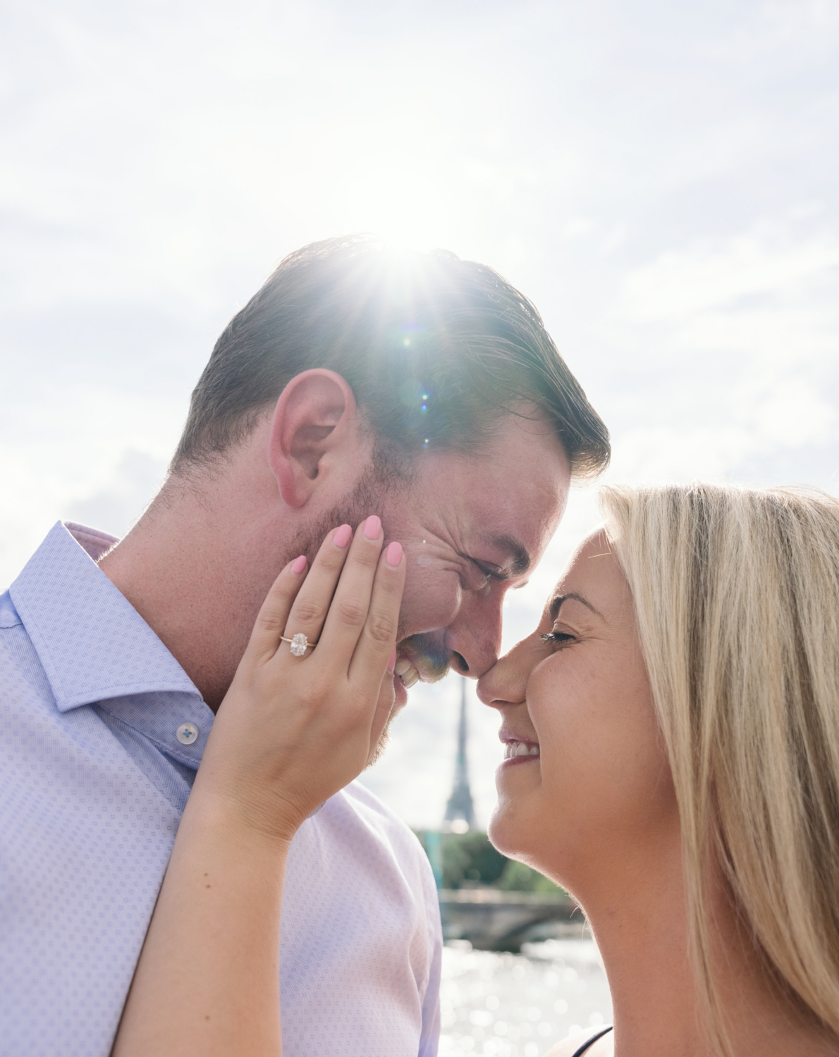 newly engaged couple smile at eat other with view of eiffel tower