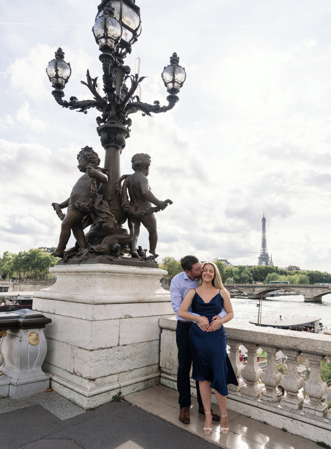 man kisses woman's cheek on pont alexandre bridge in paris